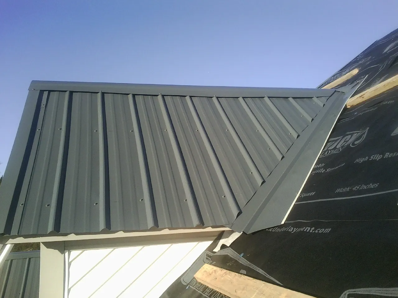 Gray metal roof panels going on over a garage gable in Lincoln