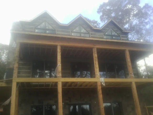 Dormers and porch framing on a large log home under construction — Roof Coating work by our crew in Lincoln